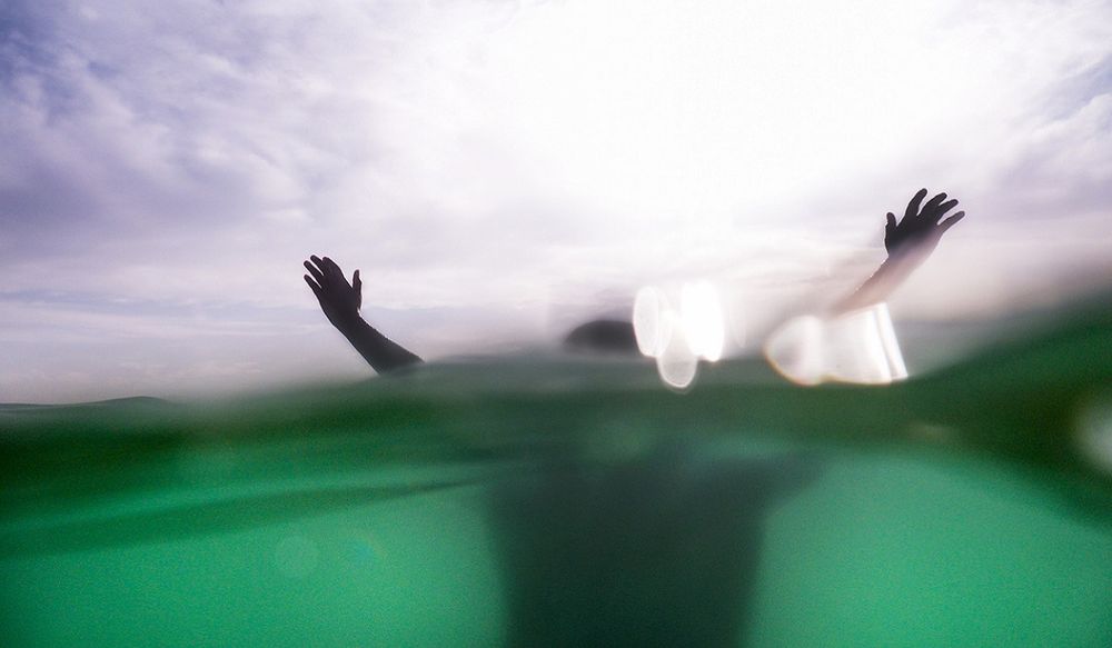 Person underwater with arms up above the water line