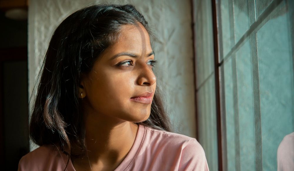 Young Indian woman looking out the window contemplatively